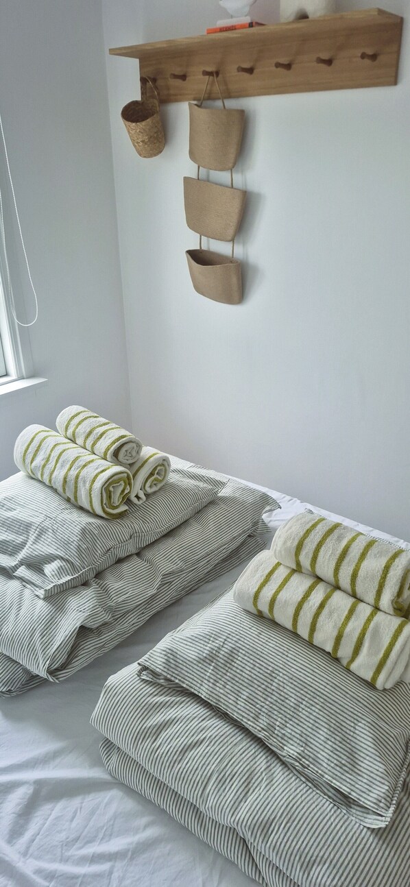 A bedroom with two beds, each with striped bedding and rolled towels.