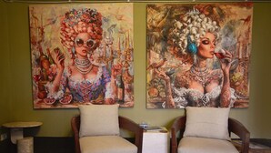 Two armchairs with cushions, a small round table, and two large paintings on the wall. - Club Carpeneto  (Carpeneto)