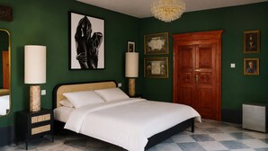 A bedroom with a bed, bedside lamps, a chandelier, a wooden door, and framed pictures on the wall.