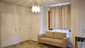 A room with a beige sofa, a patterned rug, and a chandelier.