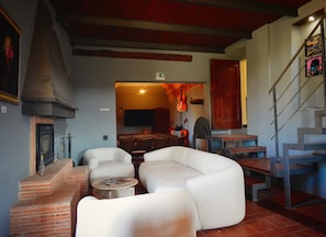 A living room with a fireplace, white sofas, a coffee table, and a staircase.