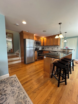 A modern kitchen with wooden cabinets, stainless steel appliances, and a central island with bar stools.