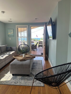 A living room with a sofa, a chair, a table, and a view of the outdoors.