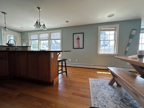 A kitchen with wooden cabinets, a countertop, a sink, a pendant light, and a window with blinds.