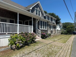 A two-story house with a porch, a driveway, and a lawn.