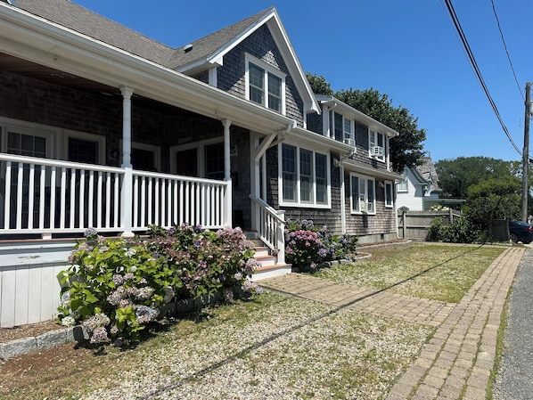 A two-story house with a porch, a driveway, and a lawn.