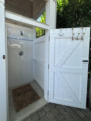 A white door with a metal latch and a small step leading to a tiled shower area.