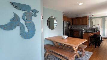 Une cuisine avec des meubles en bois, un réfrigérateur en acier inoxydable et un coin repas comprenant une table et des bancs en bois.