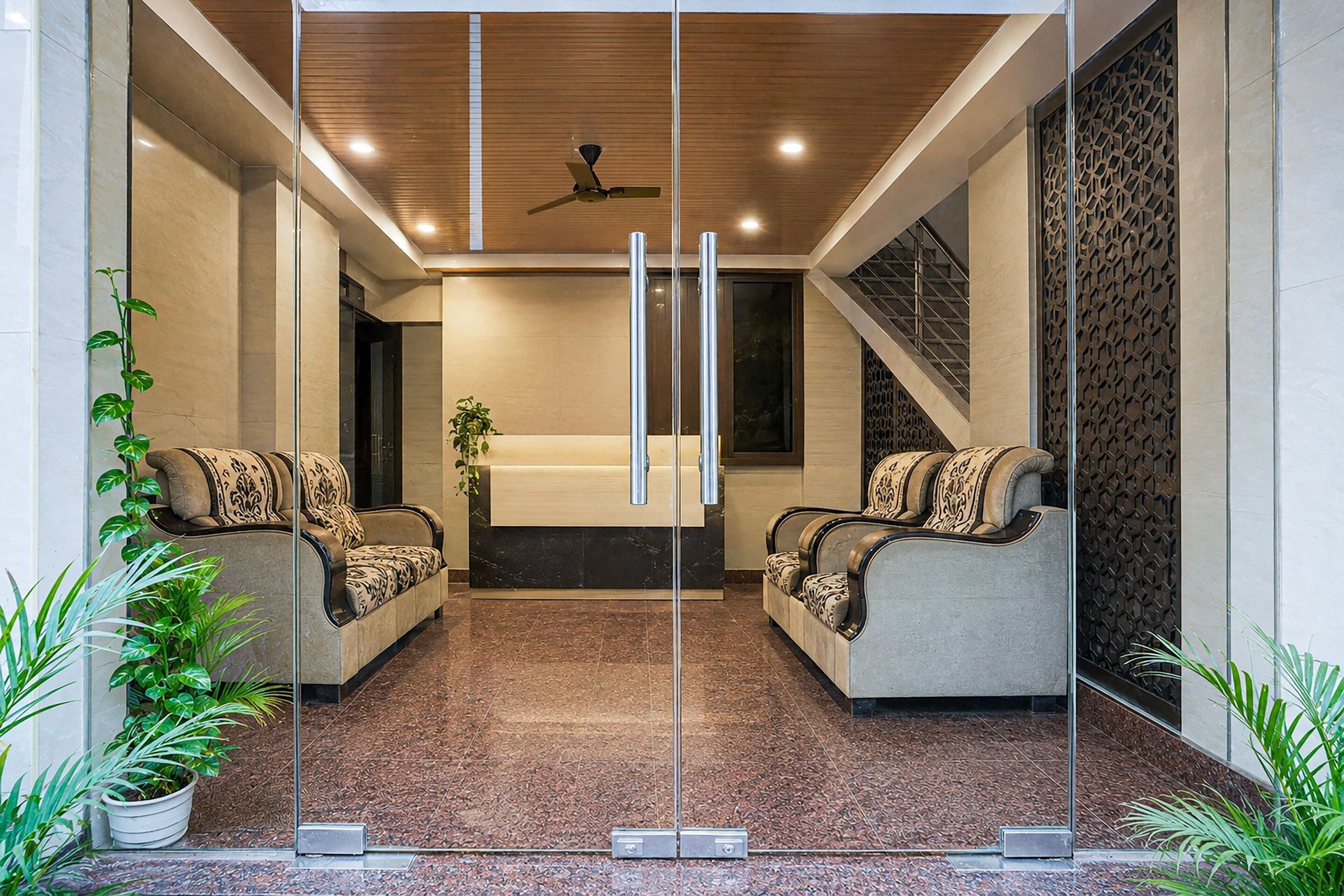A modern lobby with two sofas facing each other, a ceiling fan, and a staircase to the right.