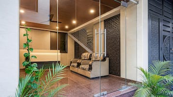 Un interior moderno con separador de vidrio, un sofá, una escalera y paneles decorativos.