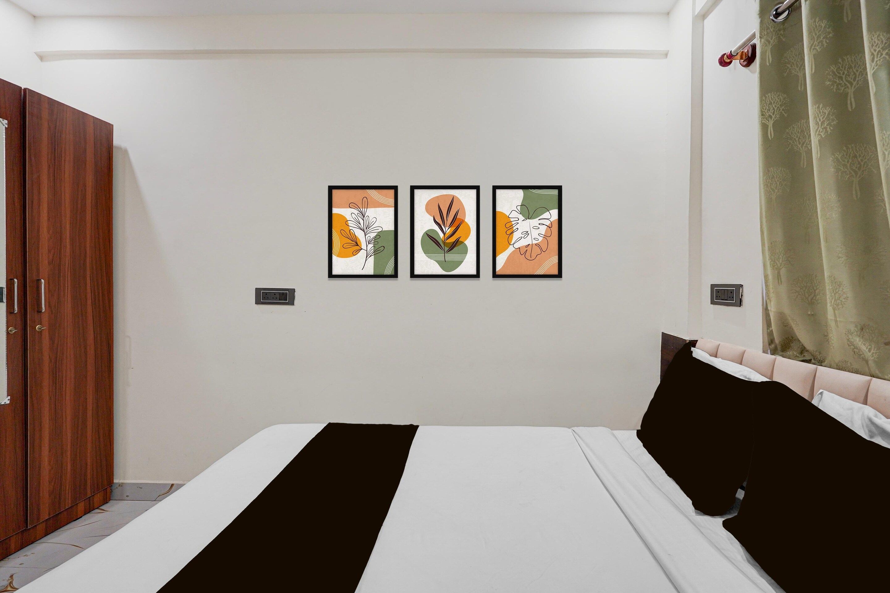 A bedroom with a bed, a wardrobe, and three framed artworks on the wall.