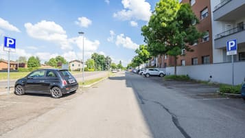Calle con coches estacionados y un edificio con un letrero de estacionamiento.