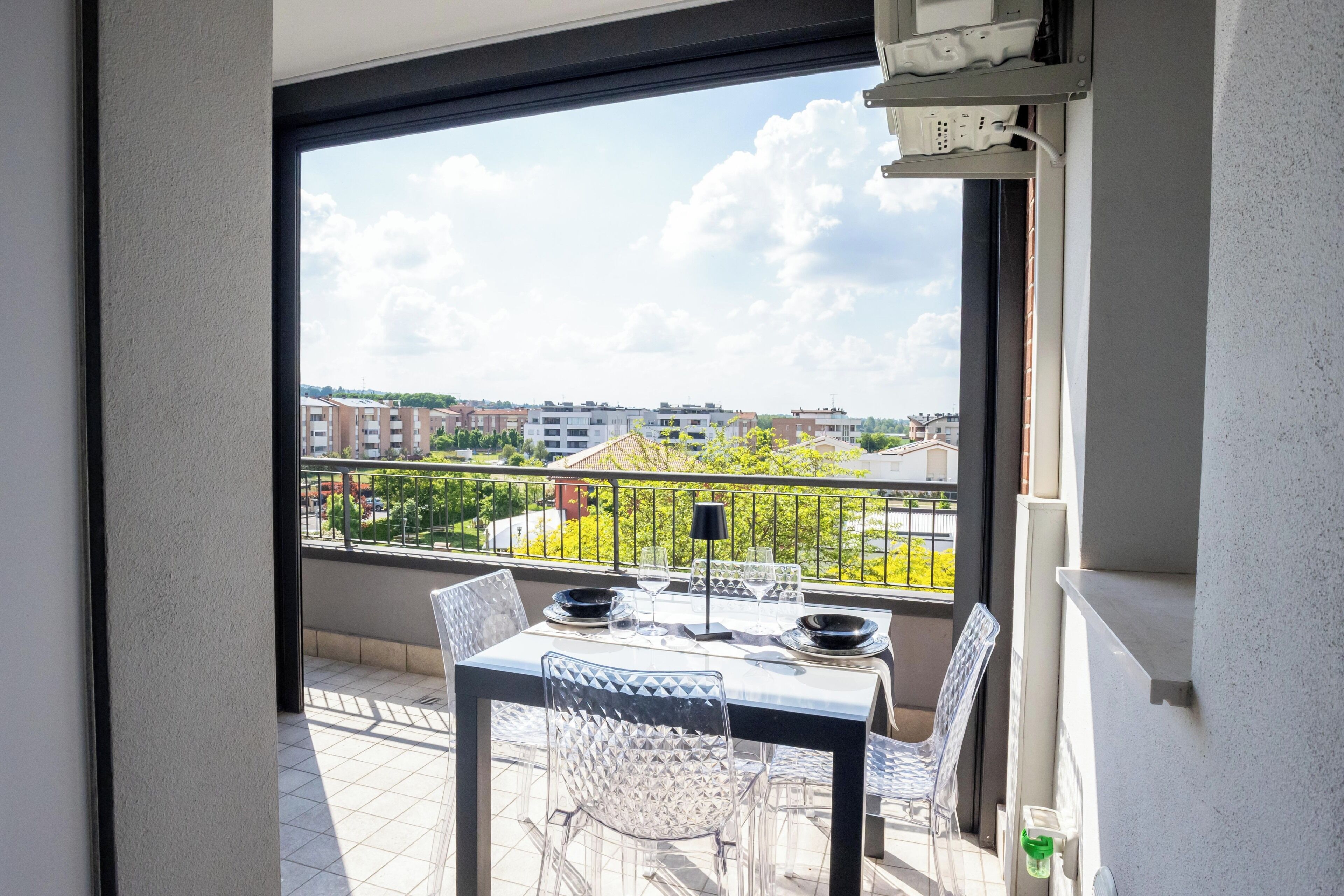 A balcony with a table set for dining, a chair, and a view of the cityscape.
