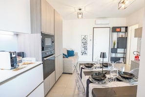 A modern kitchen with a built-in oven, a coffee machine, and a dining area with a table set for two.