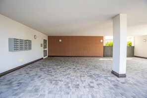 A spacious indoor area with a patterned floor, a brick wall, and a door leading outside.