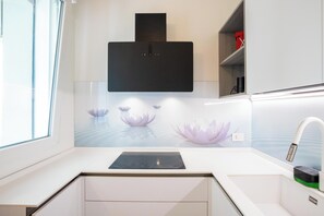 A modern kitchen with a built-in stove, a white countertop, and a wall-mounted microwave.