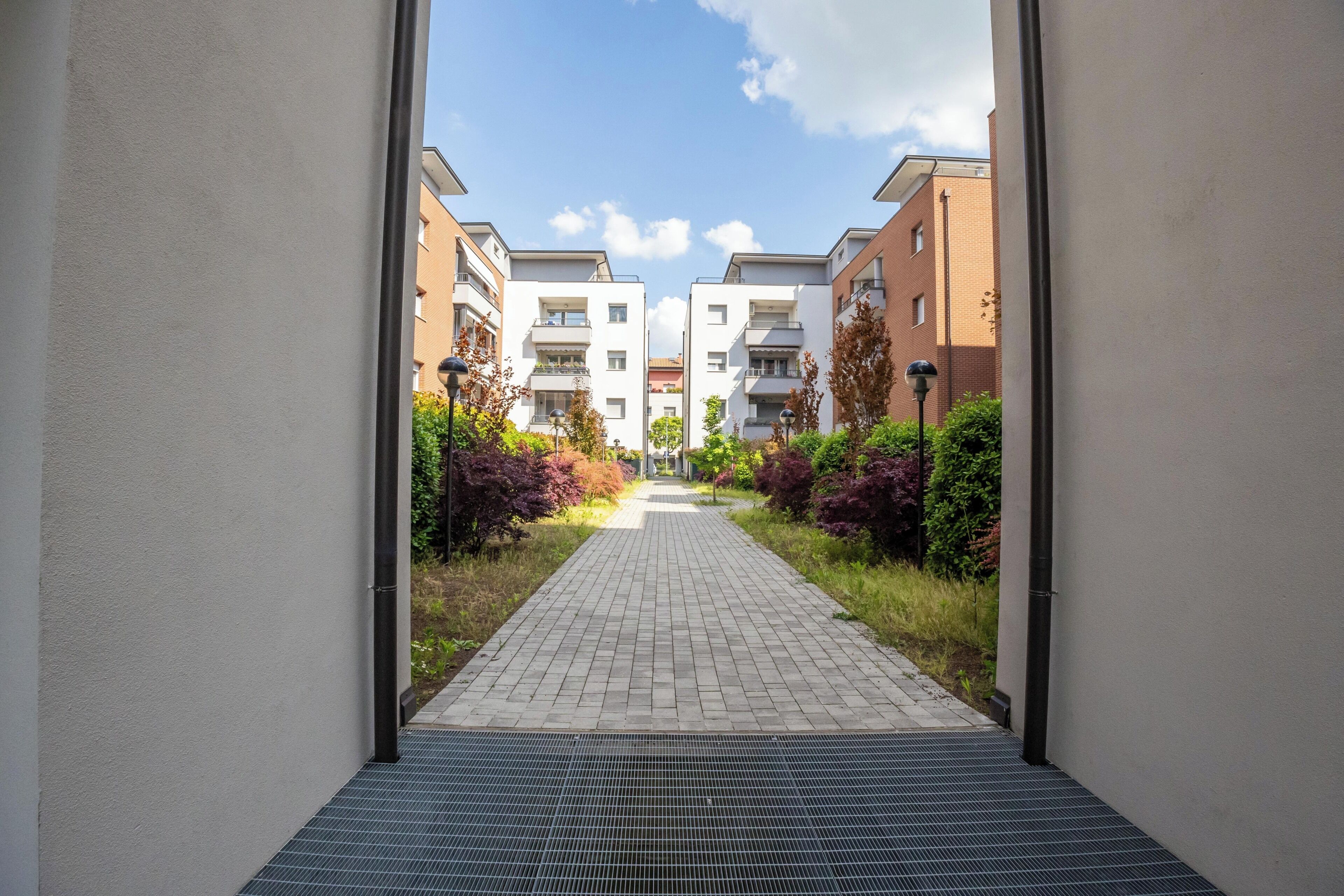 Un chemin mène à une rangée d’immeubles d’appartements modernes, avec un ciel dégagé au-dessus.