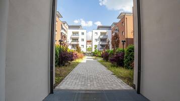 Un chemin mène à une rangée d’immeubles d’appartements modernes, avec un ciel dégagé au-dessus.