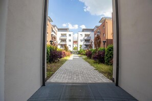 A pathway leading to a row of modern apartment buildings with a clear sky above. - Le Ninfee • Tourist Apartment (Zola Predosa)