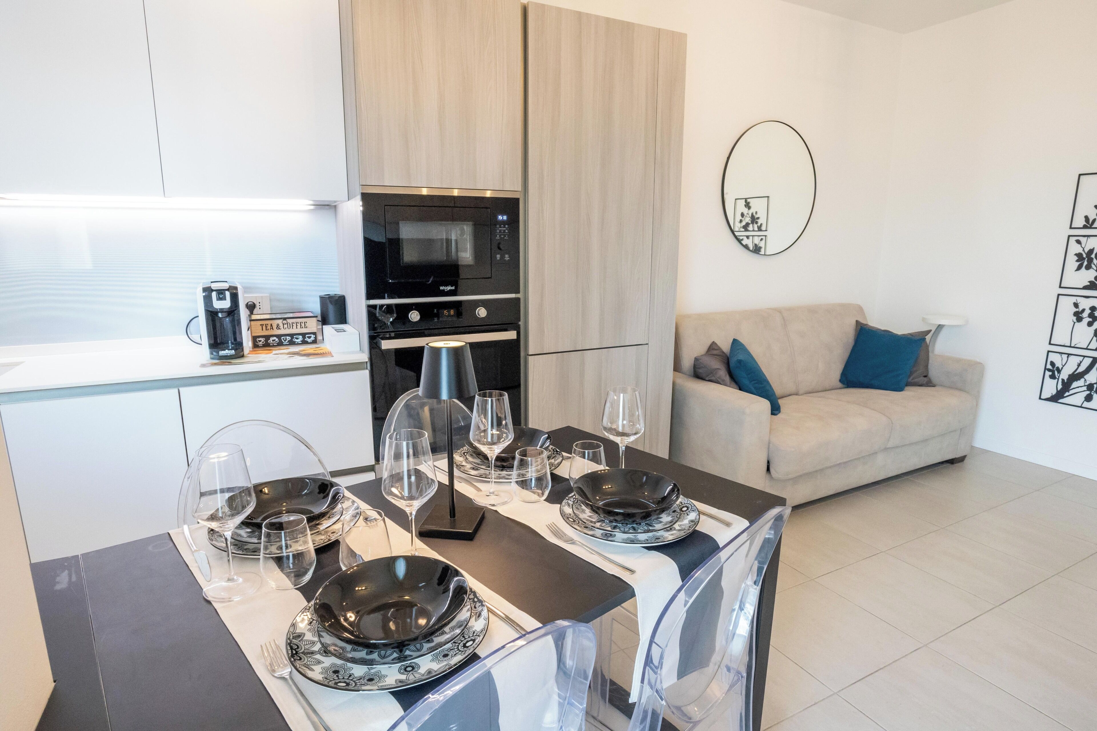 Ein moderner Wohnraum mit Essbereich, gedecktem Tisch und einer Küche mit Geräten, sowie eine Sitzecke mit Sofa.