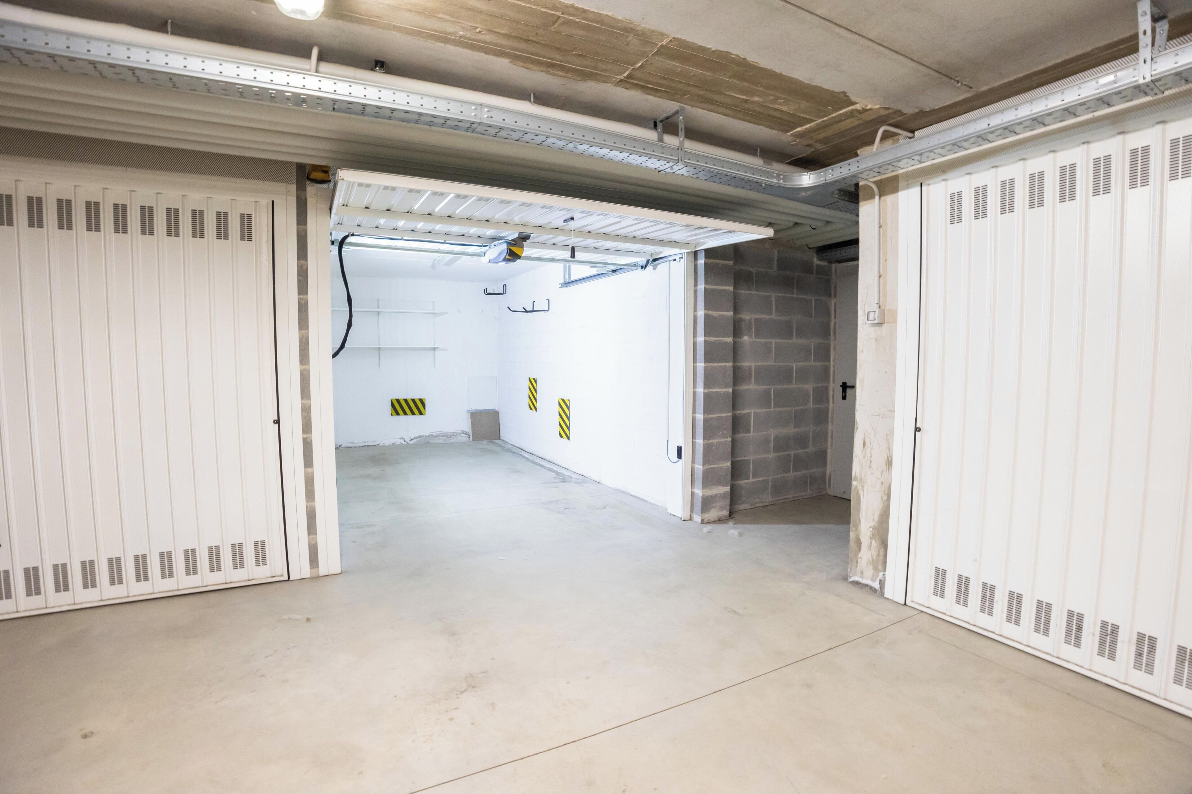 Un couloir bordé de casiers de part et d’autre, un sol en béton et un mur de briques au fond.