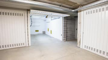 Un couloir bordé de casiers de part et d’autre, un sol en béton et un mur de briques au fond.