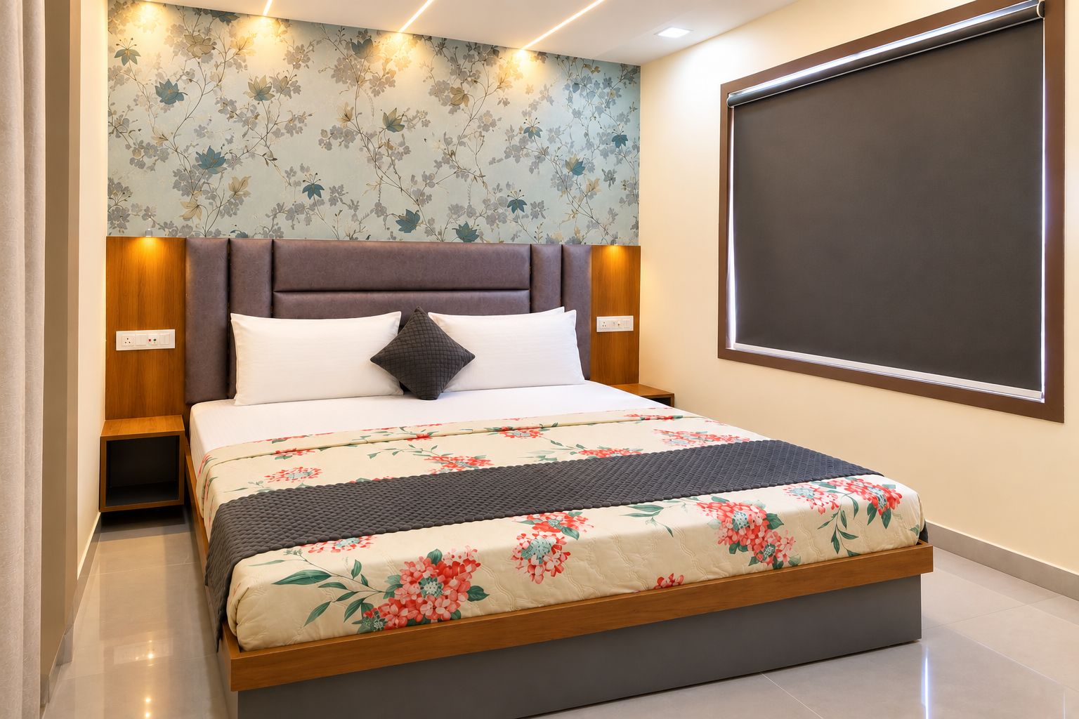 Un dormitorio con cama, mesitas de noche, cabecera, televisor montado en la pared y papel tapiz con motivos florales.