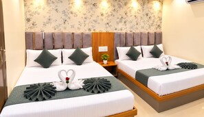 A hotel room with two beds, each with a green quilt and decorative swan pillows. - Hotel Grey Stone B & B (Amritsar)