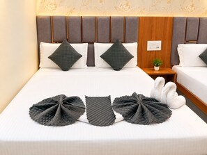 A hotel room with a bed, two pillows, a bedside table with a plant, and a wall with a floral pattern. - Hotel Grey Stone B & B (Amritsar)