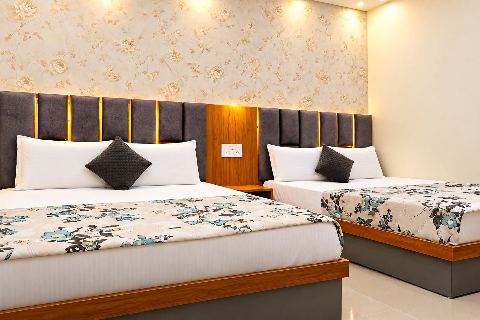 A hotel room with two beds, each with a floral bedspread and a dark headboard.