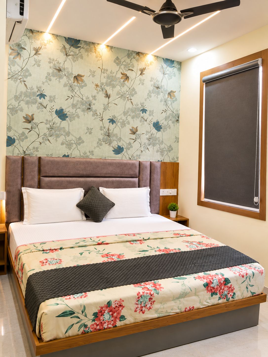 A bedroom with a bed, a headboard, a nightstand, a wall-mounted air conditioner, a ceiling fan, and a window with a blind.
