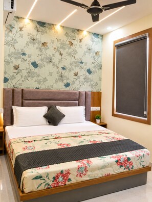 A bedroom with a bed, a headboard, a nightstand, a wall-mounted air conditioner, a ceiling fan, and a window with a blind. - Hotel Grey Stone B & B (Amritsar)