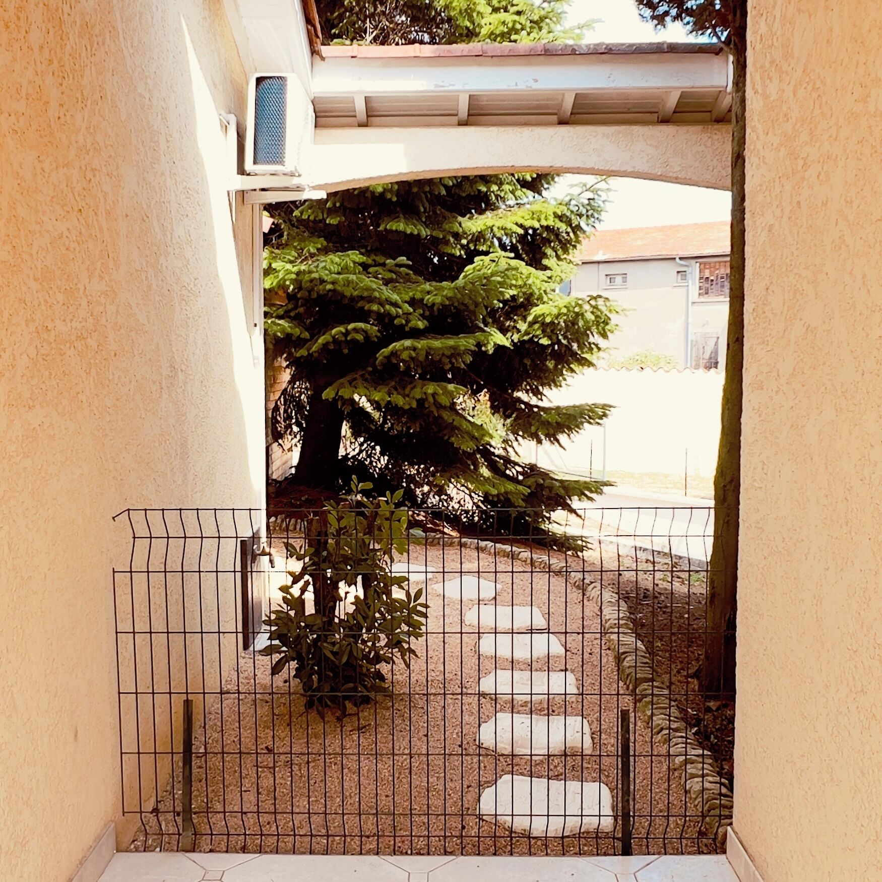 A gated outdoor area with a tree and stepping stones.