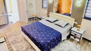 Ein Schlafzimmer mit einem Bett, Nachttischen, einem Sessel, einem Spiegel und einem Kleiderschrank.