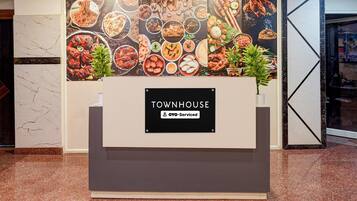 Ein Empfangsbereich mit Schildern für 'TOWNHOUSE' und 'Oyo-Serviced', die ein Serviced Hotel kennzeichnen.