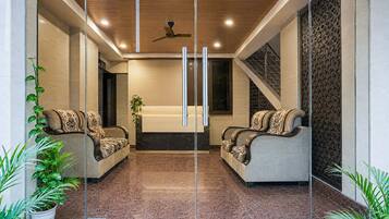 A modern lobby with two sofas facing each other, a ceiling fan, and a staircase to the right.