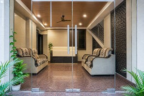 A modern lobby with two sofas facing each other, a ceiling fan, and a staircase to the right.