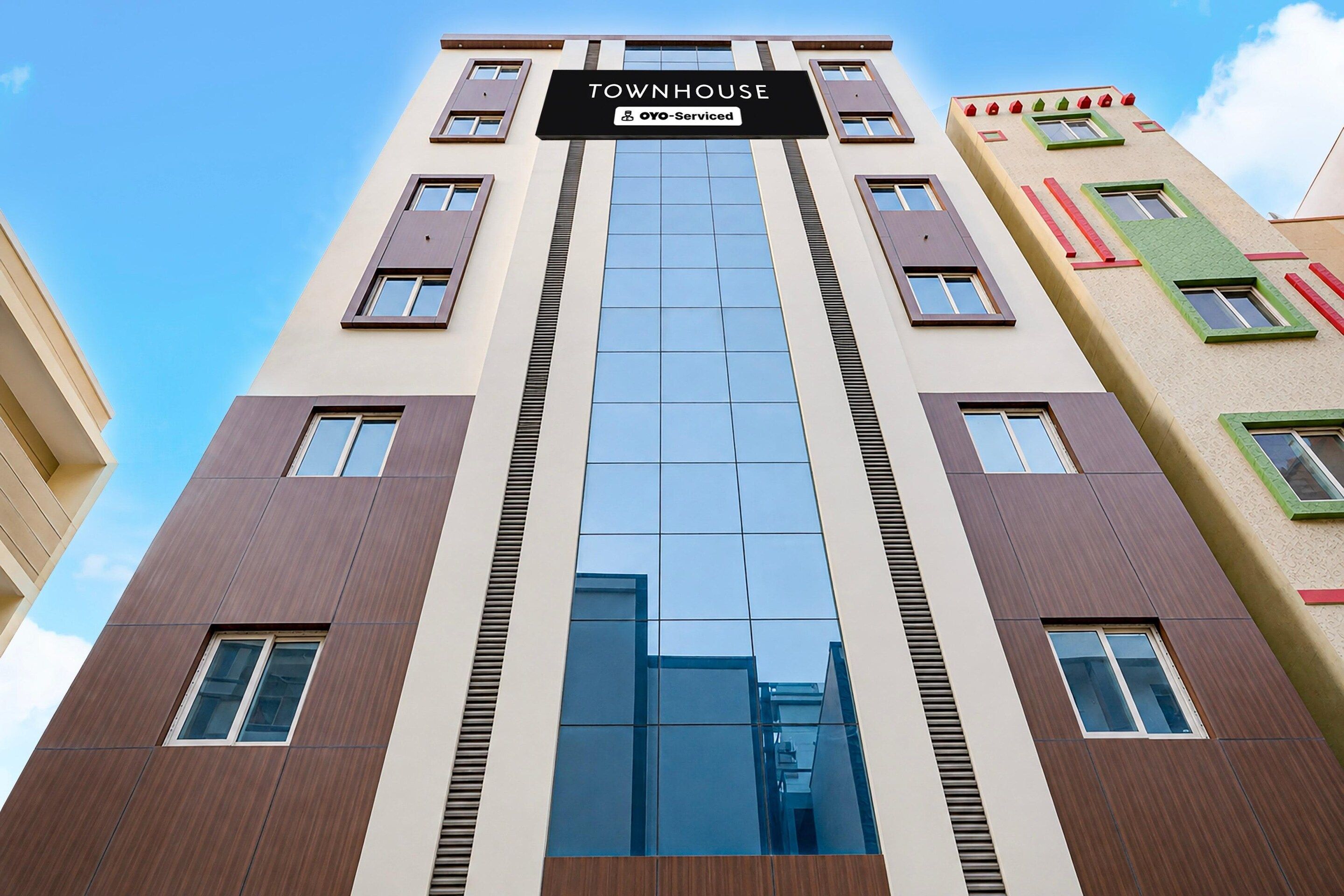A multi-story building with a sign reading 'TOWNHOUSE' and 'OYO-Serviced'.
