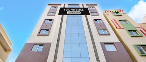 Un immeuble à plusieurs étages portant une enseigne indiquant « TOWNHOUSE » et « OYO-Serviced ».