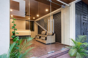 Un interior modern amb un separador de vidre, un sofà, una escala i panells decoratius.