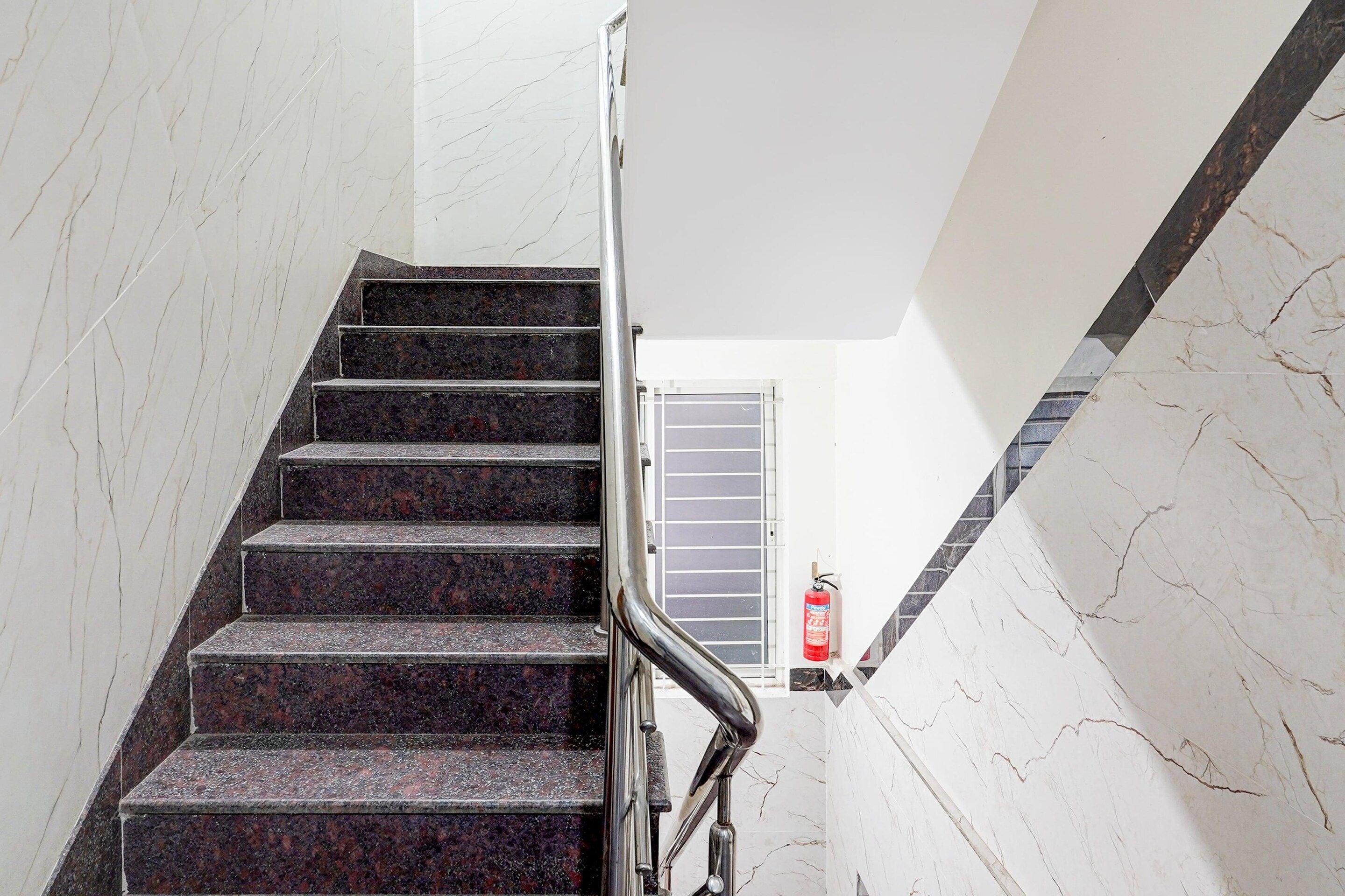 Eine Treppe mit Metallgeländer und einem an der Wand befestigten Feuerlöscher.
