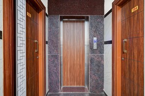 An elevator with a wooden door and a control panel with a downward arrow.