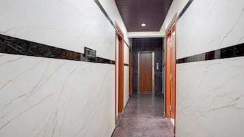 A hallway with marble walls and a red carpet leading to an elevator.