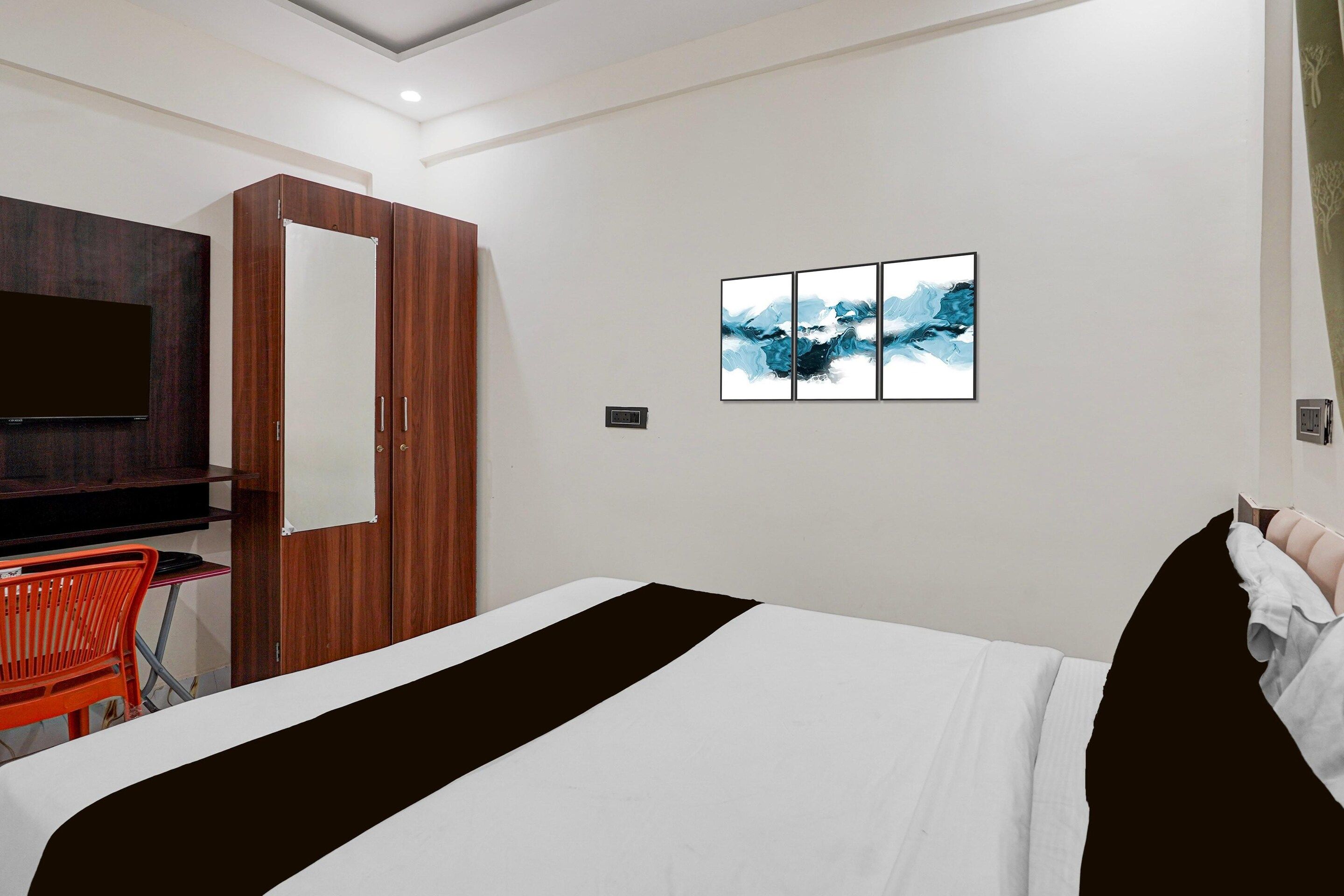 Een hotelkamer met een bed, een televisie, een kast en een kunstwerk aan de muur.