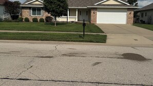 A residential house with a garage, a driveway, and a well-maintained lawn.