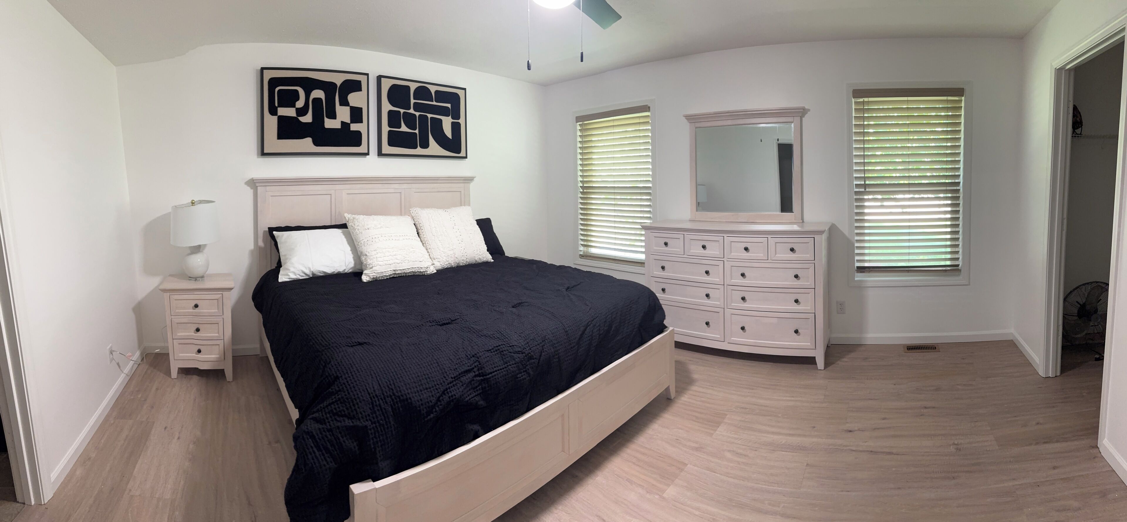 Une chambre à coucher comprenant un lit, une commode et deux miroirs fixés au mur.