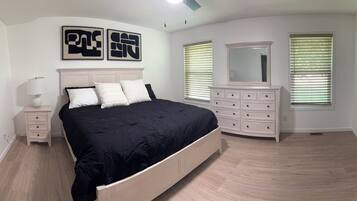 Une chambre à coucher comprenant un lit, une commode et deux miroirs fixés au mur.