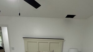 A bedroom with a bed, nightstand, lamp, and a ceiling fan.
