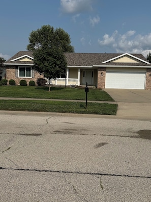 A residential house with a garage, a lawn, and a mailbox.