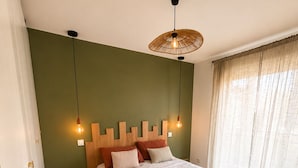 A bedroom with a bed, a bedside table, a lamp, and a window with curtains. - Cozy, air-conditioned 2-bedroom apartment, Toulon (Toulon)